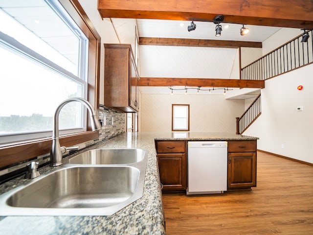 kitchen featuring sink, dishwasher, tasteful backsplash, lofted ceiling with beams, and light hardwood / wood-style floors