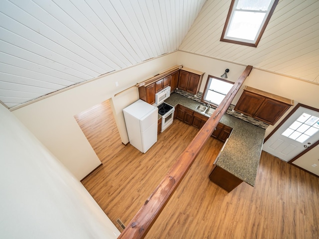 kitchen with lofted ceiling with skylight, sink, wooden ceiling, white appliances, and light hardwood / wood-style floors