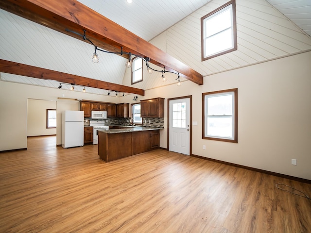 kitchen with lofted ceiling with beams, kitchen peninsula, white appliances, a healthy amount of sunlight, and decorative backsplash