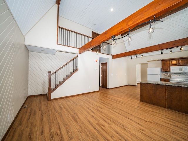 unfurnished living room with beamed ceiling, rail lighting, high vaulted ceiling, and light hardwood / wood-style flooring