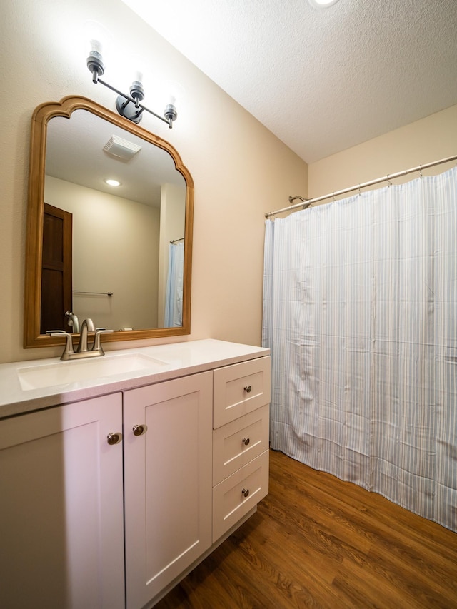 bathroom featuring hardwood / wood-style flooring, vanity, and a textured ceiling