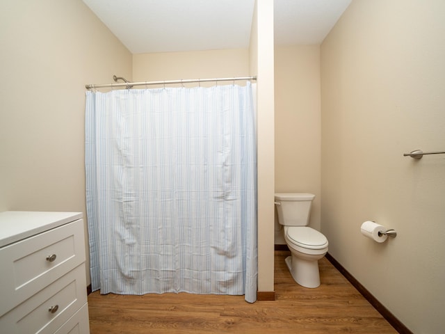 bathroom with walk in shower, toilet, and hardwood / wood-style floors