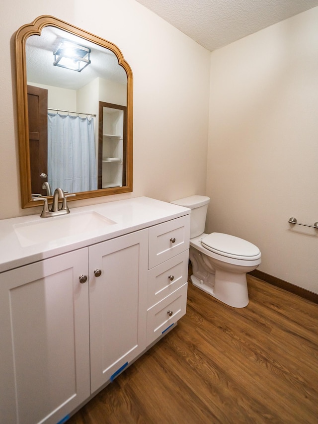 bathroom with hardwood / wood-style flooring, vanity, toilet, and a textured ceiling