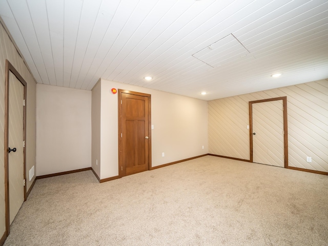 basement with light colored carpet and wood walls