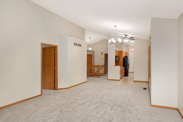 carpeted empty room with lofted ceiling and an inviting chandelier