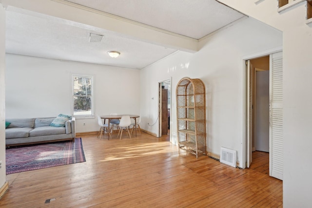 interior space with beam ceiling, visible vents, a textured ceiling, wood finished floors, and baseboards