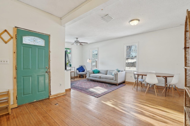 entrance foyer featuring a textured ceiling, wood finished floors, a ceiling fan, visible vents, and baseboards