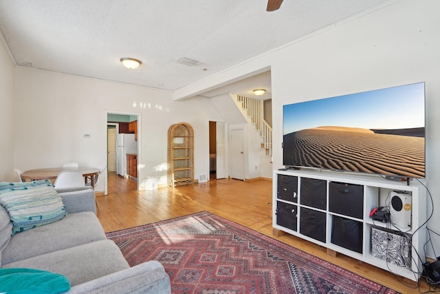 living room with light wood-style flooring, a textured ceiling, and stairs