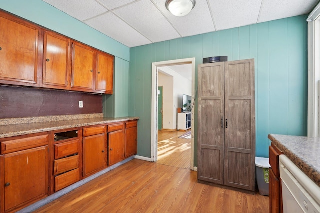 kitchen with dishwasher, a drop ceiling, light wood-style flooring, brown cabinets, and light countertops