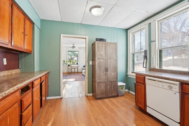 kitchen with baseboards, light wood finished floors, white dishwasher, and brown cabinets