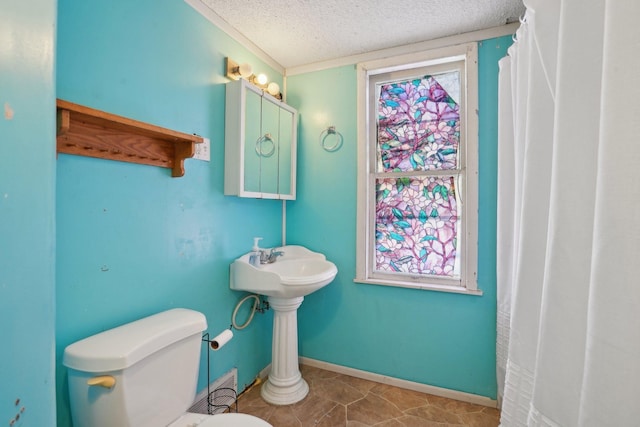 full bathroom with a textured ceiling, plenty of natural light, toilet, and baseboards