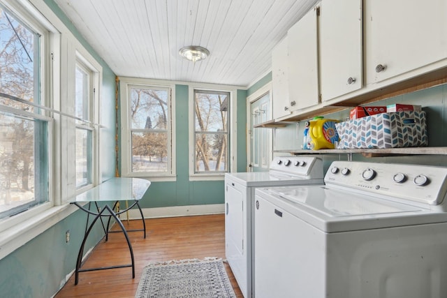 laundry area with light wood-type flooring, cabinet space, plenty of natural light, and washer and clothes dryer