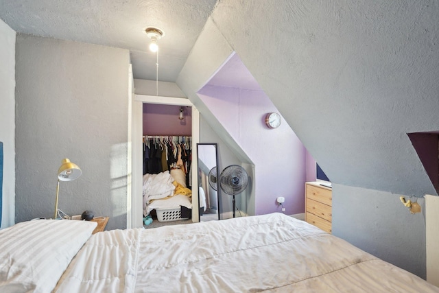 bedroom featuring lofted ceiling, a closet, and a textured ceiling