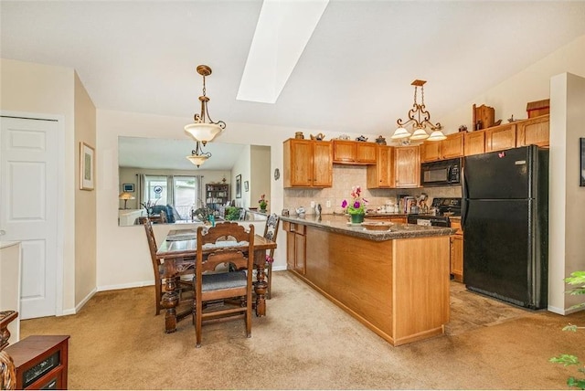 kitchen with black appliances, hanging light fixtures, light carpet, vaulted ceiling with skylight, and backsplash