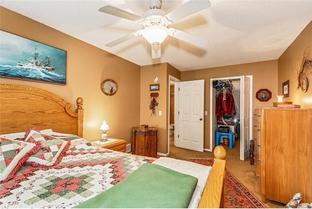 carpeted bedroom with a textured ceiling, a closet, ceiling fan, and a walk in closet