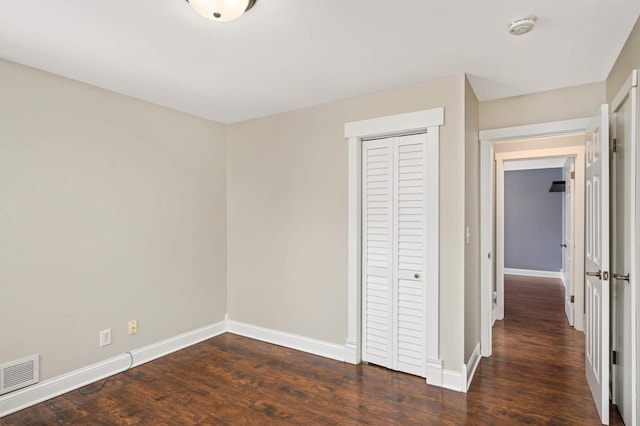 unfurnished bedroom with dark hardwood / wood-style floors and a closet