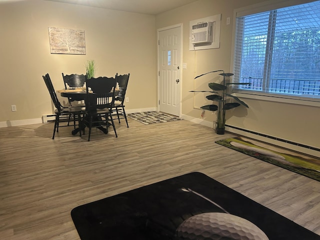 dining area with hardwood / wood-style flooring, a baseboard radiator, and an AC wall unit