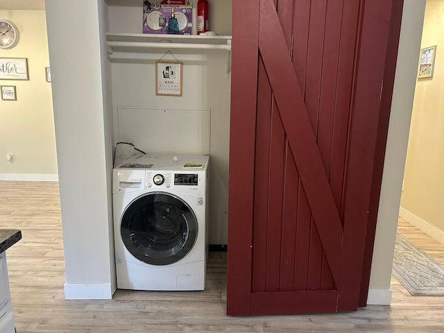 laundry room with washer / clothes dryer and light hardwood / wood-style flooring