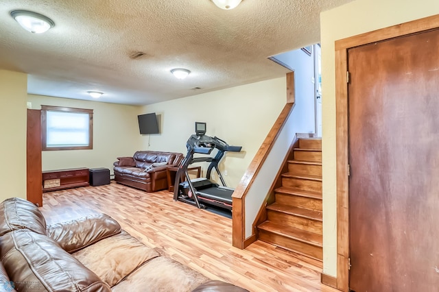 exercise room with wood-type flooring and a textured ceiling