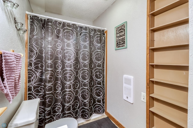 bathroom featuring curtained shower, a textured ceiling, and toilet