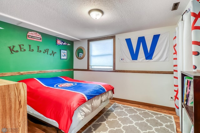 bedroom with hardwood / wood-style floors and a textured ceiling