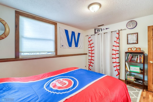 bedroom featuring hardwood / wood-style floors and a textured ceiling