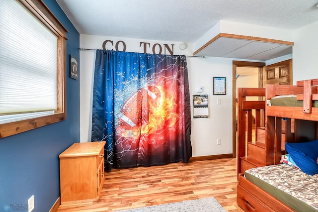 bedroom with multiple windows, a textured ceiling, and light hardwood / wood-style floors