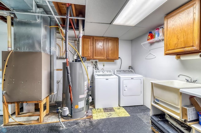 laundry area with heating unit, water heater, sink, cabinets, and washer and clothes dryer