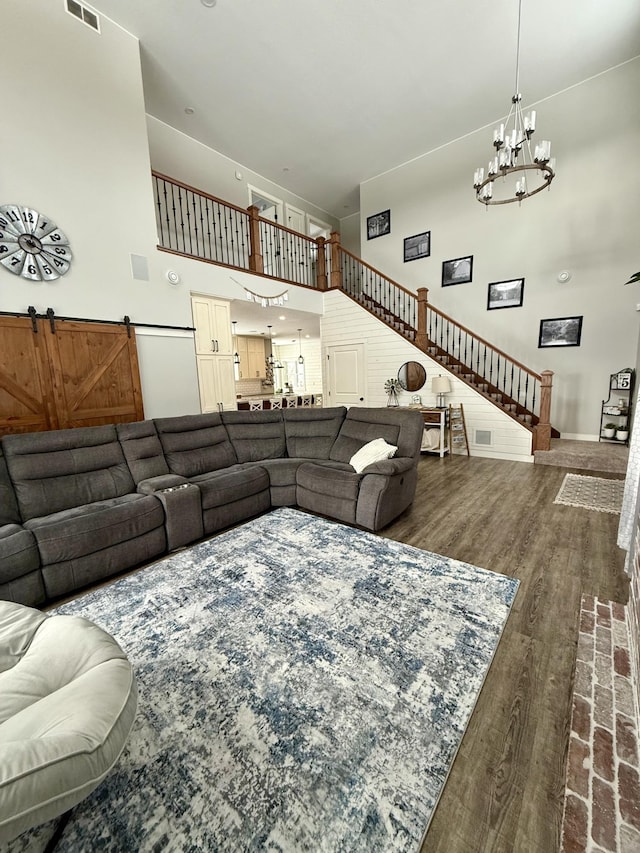 living room with a towering ceiling, a chandelier, and hardwood / wood-style floors