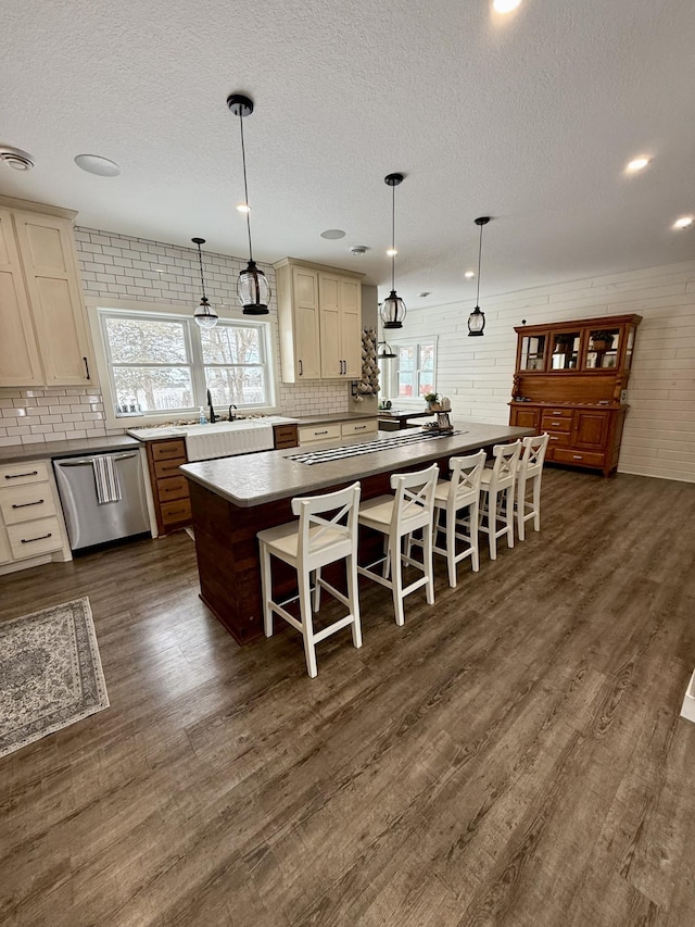 kitchen featuring a center island, stainless steel dishwasher, dark wood-type flooring, and decorative light fixtures