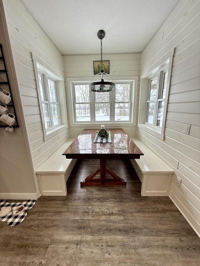 unfurnished dining area featuring breakfast area, wooden walls, and dark hardwood / wood-style floors