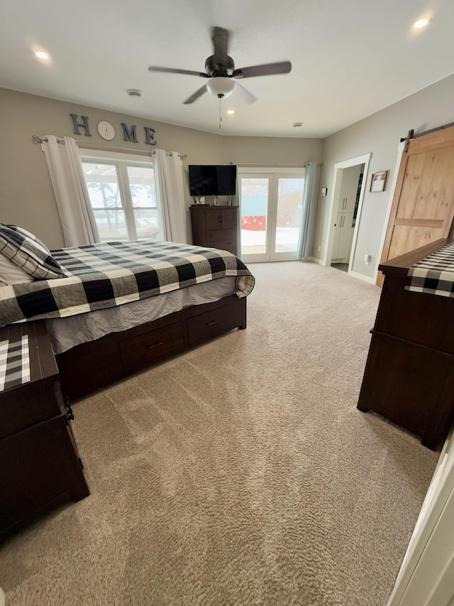 bedroom with a barn door, ceiling fan, carpet flooring, and multiple windows