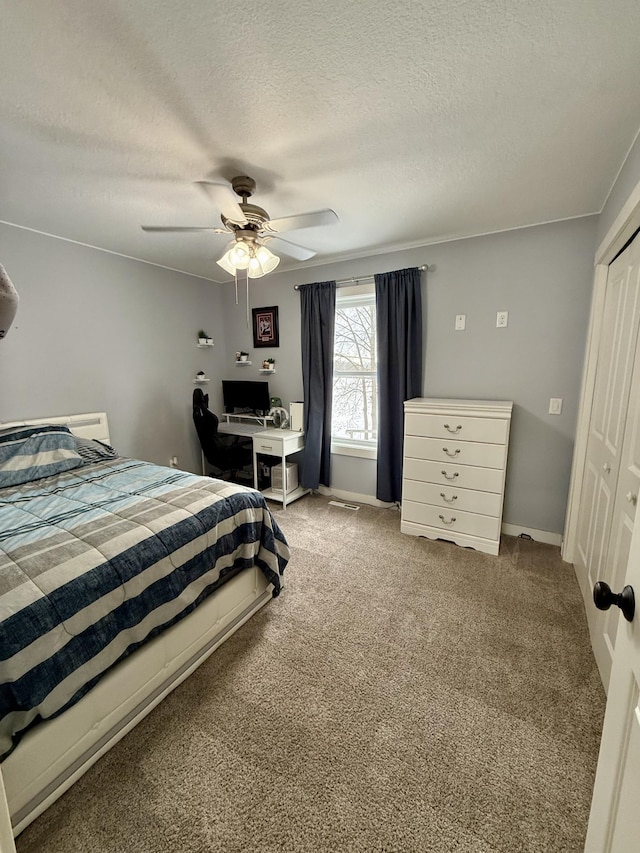 carpeted bedroom with ceiling fan, a closet, and a textured ceiling