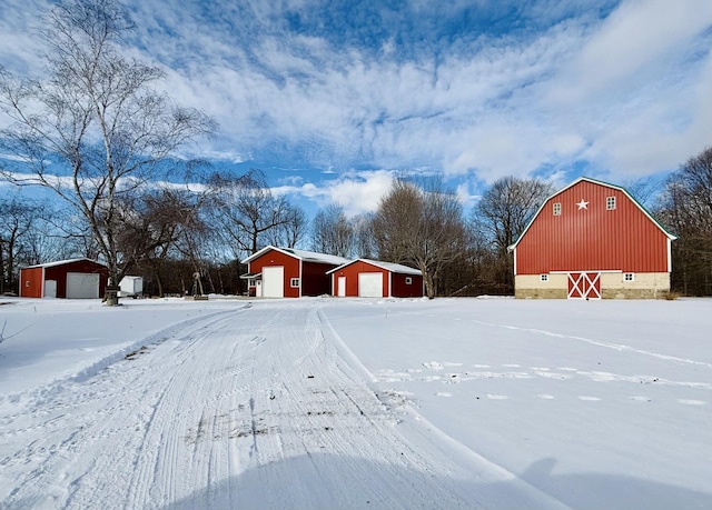 yard covered in snow featuring a garage and an outdoor structure