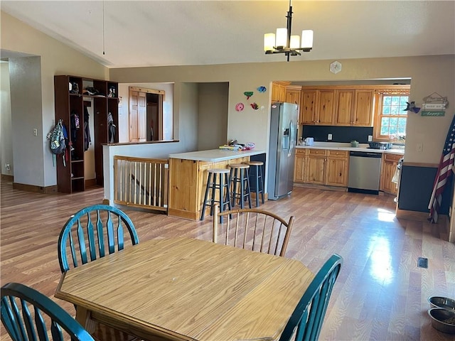 dining room featuring vaulted ceiling, a chandelier, and light hardwood / wood-style flooring