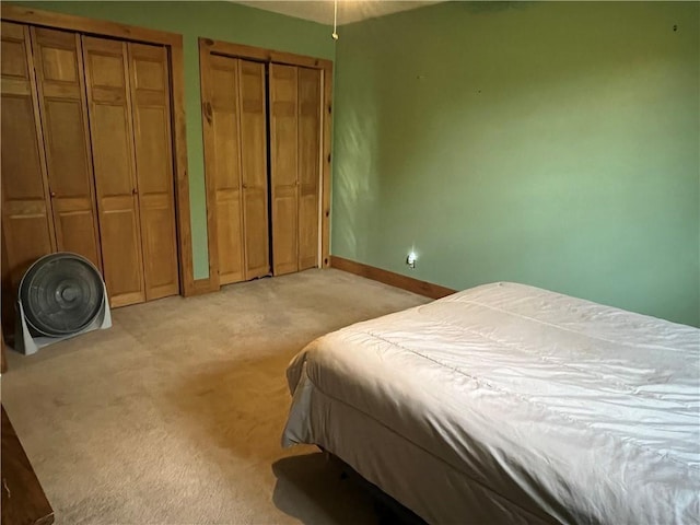 bedroom featuring multiple closets and light carpet