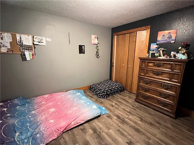 bedroom with wood-type flooring, a textured ceiling, and a closet