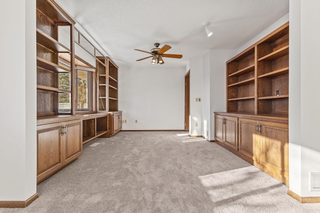 unfurnished living room with ceiling fan, light carpet, and a textured ceiling