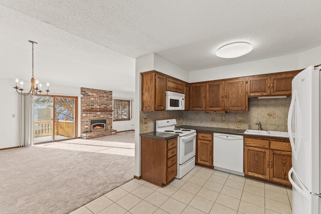 kitchen featuring sink, white appliances, hanging light fixtures, a textured ceiling, and light carpet