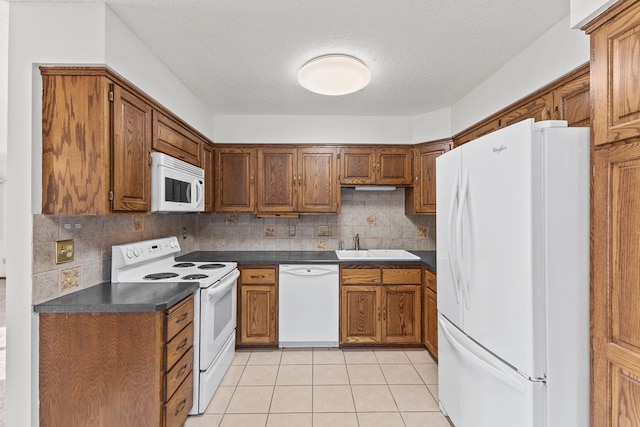 kitchen with sink, backsplash, light tile patterned floors, white appliances, and a textured ceiling