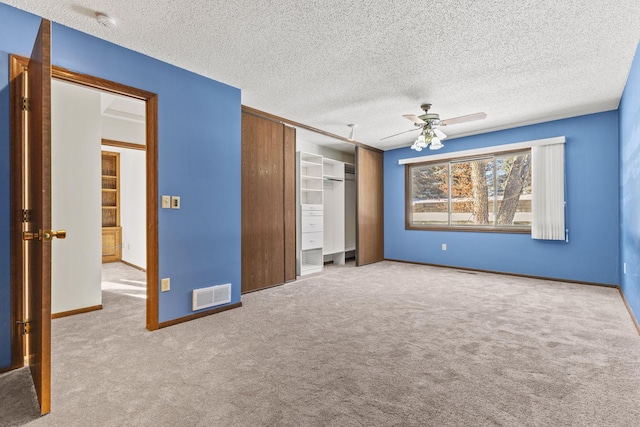 unfurnished bedroom with a closet, ceiling fan, light colored carpet, and a textured ceiling