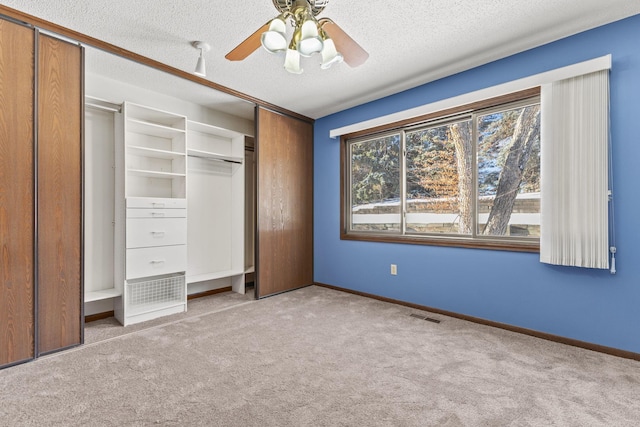 unfurnished bedroom featuring light carpet, a textured ceiling, and ceiling fan