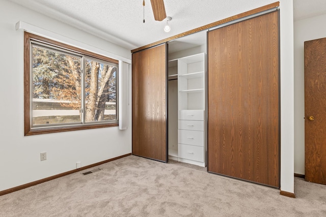 unfurnished bedroom featuring light colored carpet, a textured ceiling, ceiling fan, and a closet