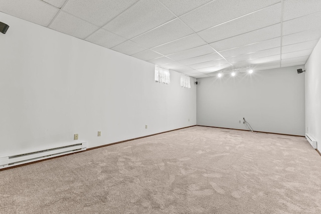 basement with a baseboard heating unit, a paneled ceiling, and carpet flooring