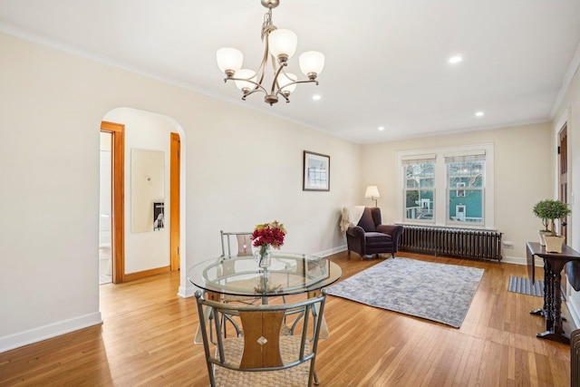 living area with light wood-type flooring, radiator heating unit, ornamental molding, and an inviting chandelier