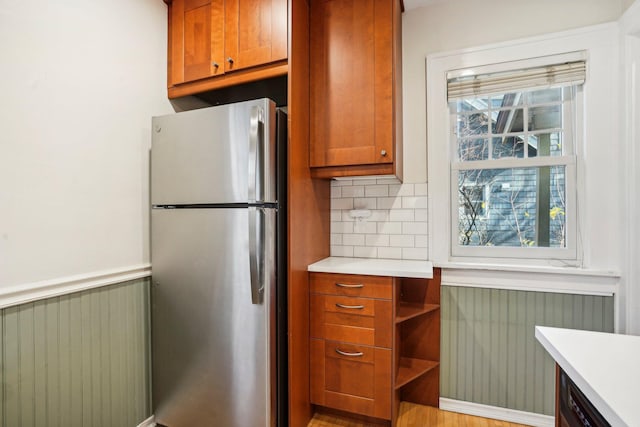 kitchen with a wealth of natural light, radiator heating unit, tasteful backsplash, and stainless steel fridge