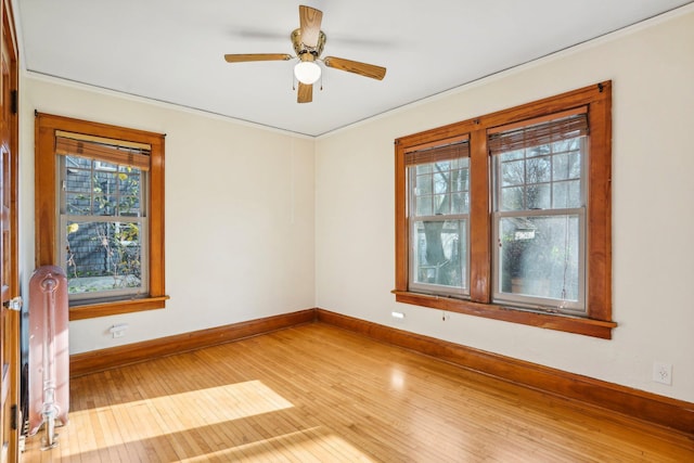 empty room featuring wood-type flooring, radiator, and ceiling fan