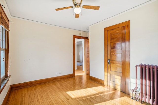 empty room with radiator heating unit, light hardwood / wood-style floors, and ceiling fan