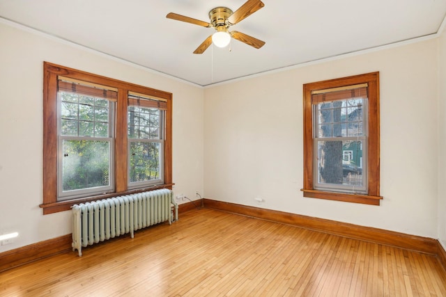 empty room featuring light hardwood / wood-style floors, radiator, and a wealth of natural light