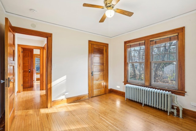 spare room featuring ceiling fan, radiator, and light hardwood / wood-style flooring